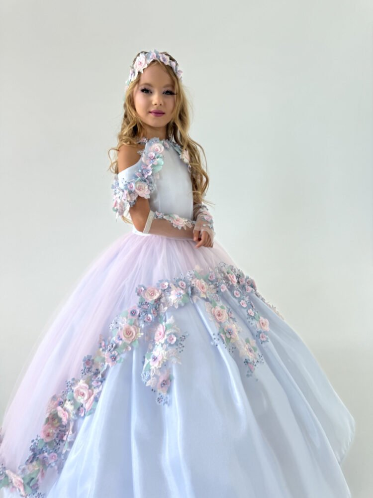 Florence gown for girls in white and lavender with cold shoulder sleeves, pastel floral appliqués, and voluminous tulle skirt—styled with matching floral headpiece for weddings, pageants, and princess-themed events.