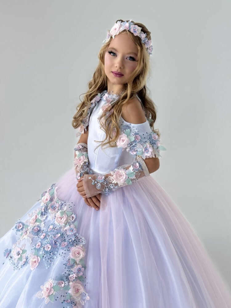 Florence gown for girls in white and blush pink with off-the-shoulder sleeves, pastel floral appliqués, and voluminous tulle skirt—styled with matching headband and arm accessories for weddings, pageants, and princess-themed events.