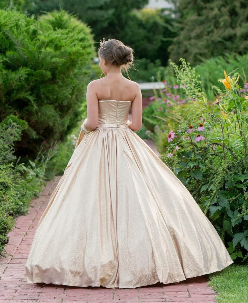 Grace champagne ball gown with strapless fitted bodice and voluminous skirt—styled in a garden setting with blooming flowers for weddings, fantasy shoots, and royal-themed celebrations.
