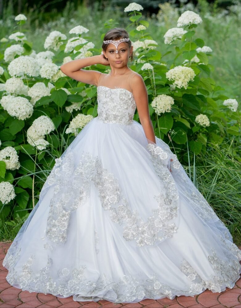 Layla white ball gown with silver floral embroidery, layered tulle skirt, and jeweled headband—styled outdoors on a brick pathway with blooming hydrangeas for weddings, fantasy shoots, and royal-themed celebrations.
