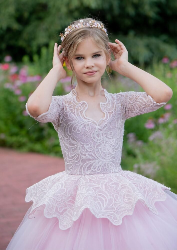 Rosie light pink ball gown with scalloped lace neckline, floral lace sleeves, and layered tulle skirt—styled outdoors in a garden with blooming flowers for weddings, fantasy shoots, and royal-themed celebrations.