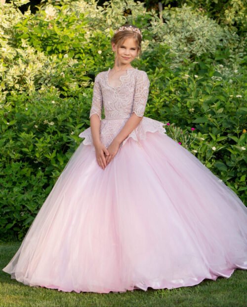 Rosie light pink ball gown with embroidered bodice, three-quarter sleeves, peplum waist, and voluminous tulle skirt—styled outdoors in a garden setting for weddings, fantasy shoots, and royal-themed celebrations.