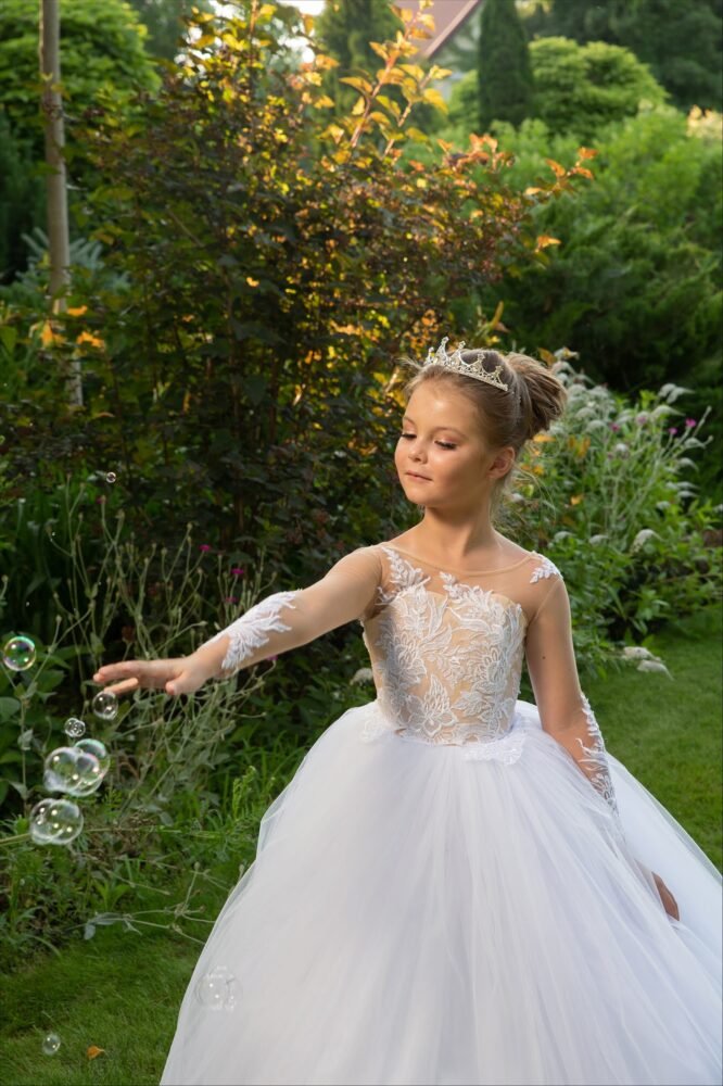 THEA white ball gown with lace sleeves, scalloped neckline, and full tulle skirt—styled outdoors in a sunlit garden with tiara and floating bubbles for weddings, fantasy shoots, and royal-themed celebrations.
