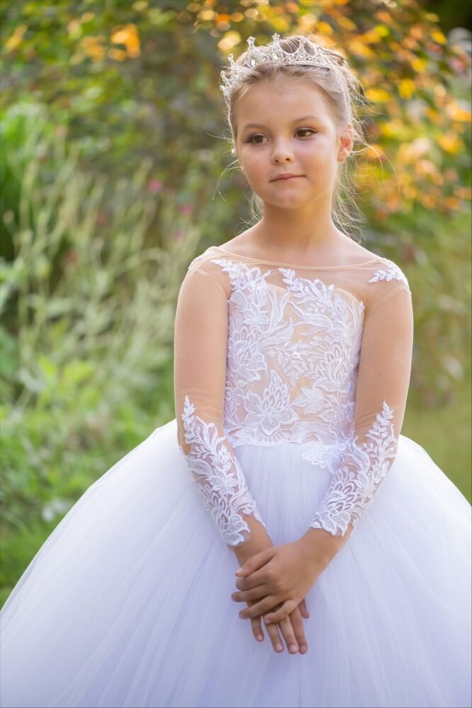 THEA white ball gown with off-the-shoulder lace sleeves, floral lace bodice, and full tulle skirt—styled outdoors in a sunlit garden with tiara for weddings, fantasy shoots, and royal-themed celebrations.